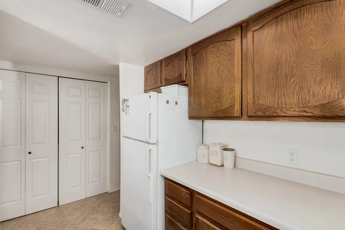 A modern kitchen scene featuring sleek cabinets, a stainless steel refrigerator, ample counter space, and various kitchen accessories. The image conveys a sense of activity, with the space prepared for meal preparation or family gatherings. The overall mood is welcoming and practical, emphasizing the kitchen as the heart of the home.